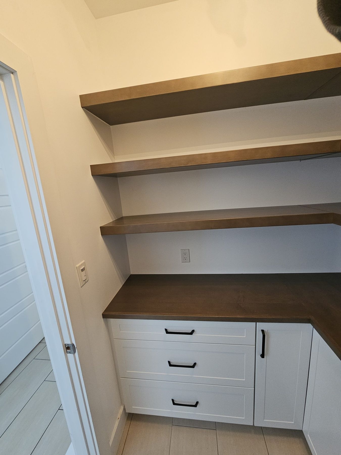 Floating wood shelves over a deep drawer bank in a walk-in pantry